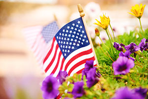 A small American flag sourrounded by flowers.