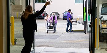 Welcoming with a wave a participant and aide. Bus driver in background