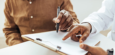 man signing document on clipboard