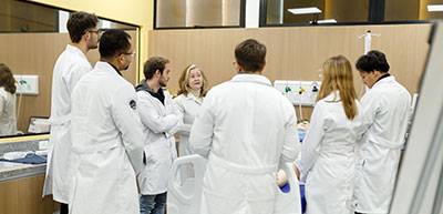 medical students with backs to camera in classroom listening to teacher in a hospital or clinic setting