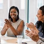 diverse colleagues clapping and sitting at conference table