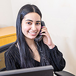 Smiling PACE center receptionist at desk on phone