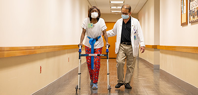 PT OT or rehab tech assisting participant with walking down hallway